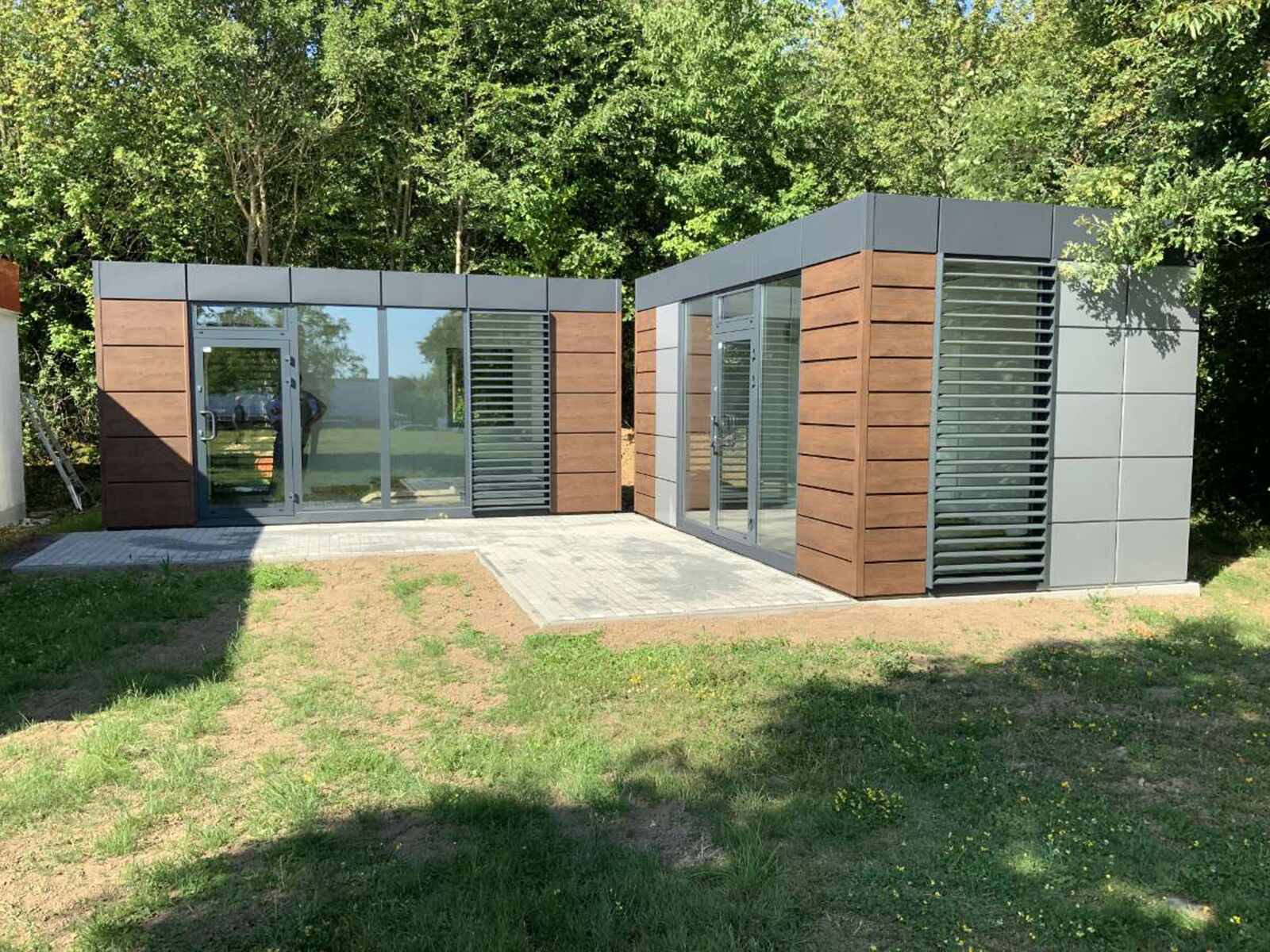 Zwei moderne Modulcontainer mit Holz- und Metallfassade im Grünen