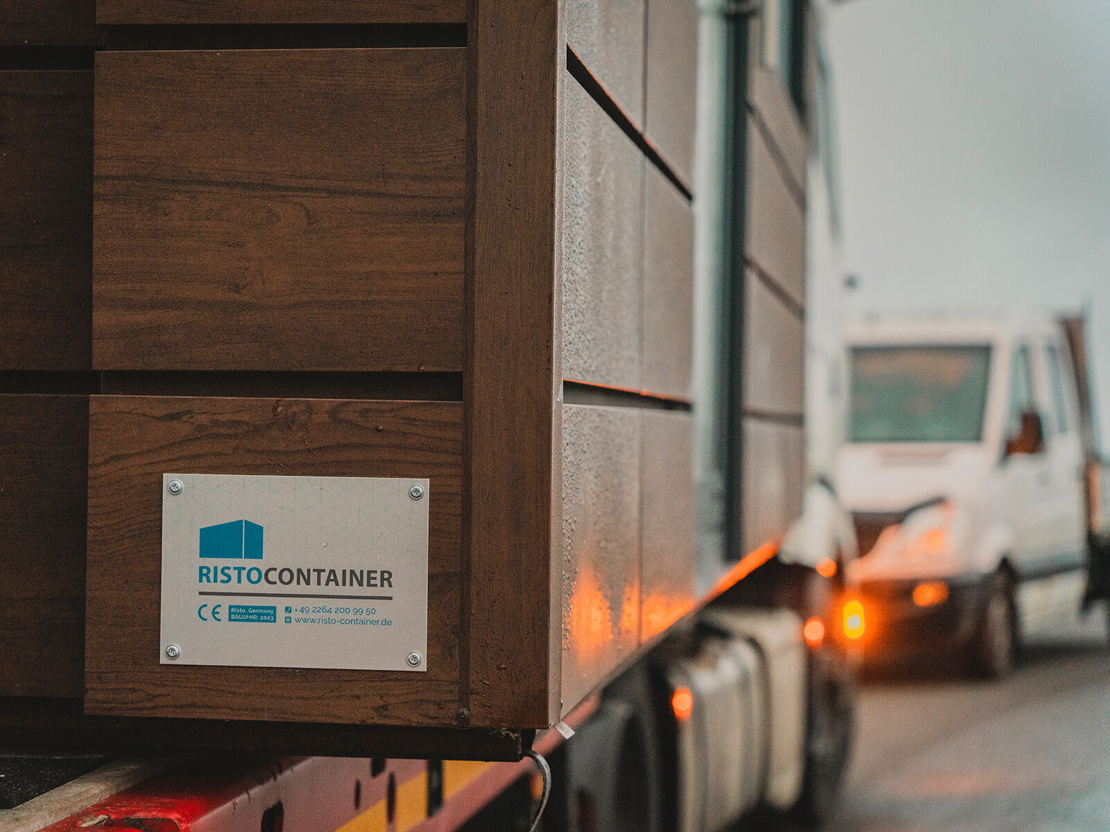 Ristocontainer Modul mit Holzfassade beim Transport auf einem Lkw-Anhänger