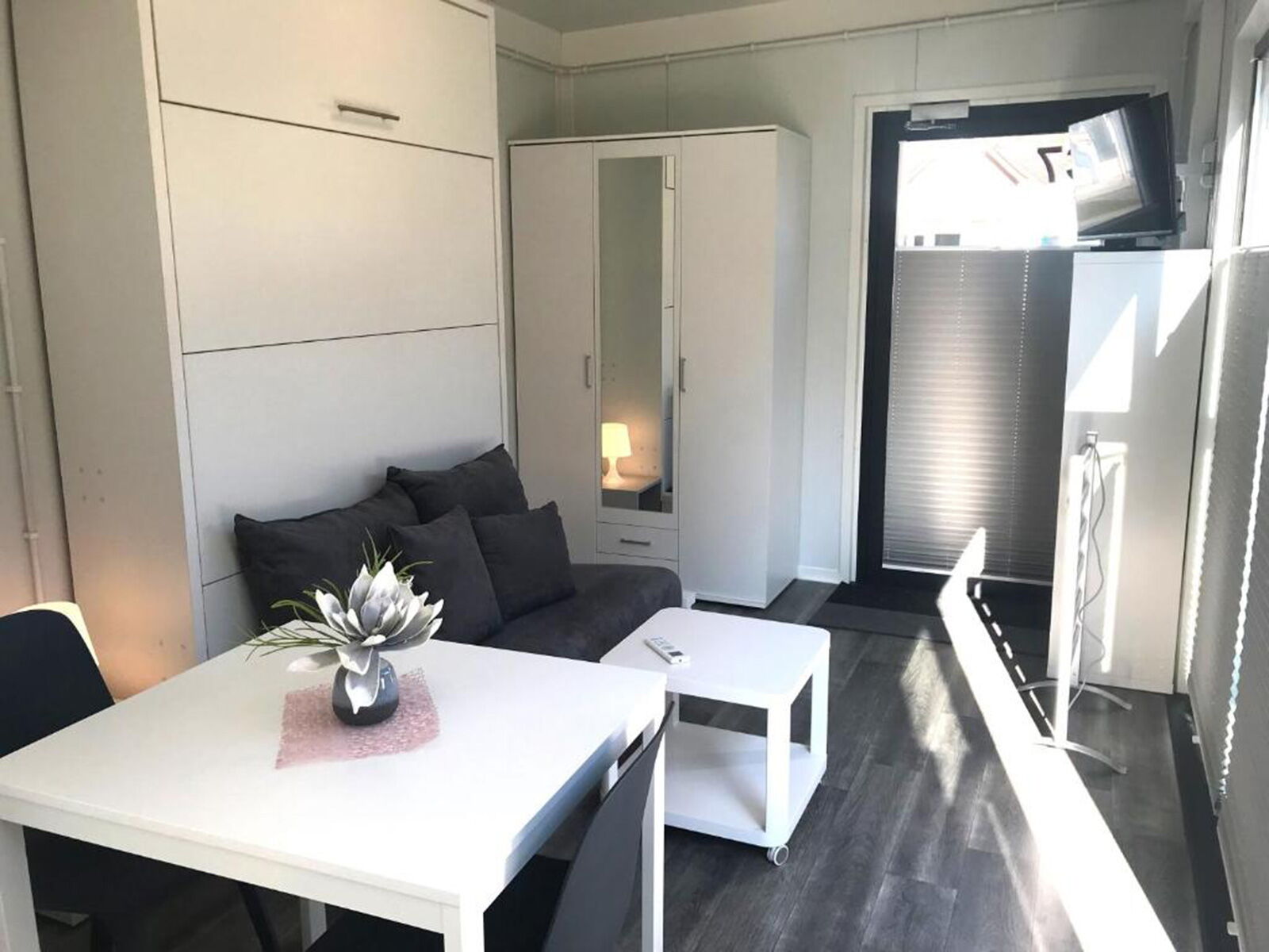 Innenraum eines Wohncontainers mit Sofa, Esstisch, Schrank und moderner Einrichtung
