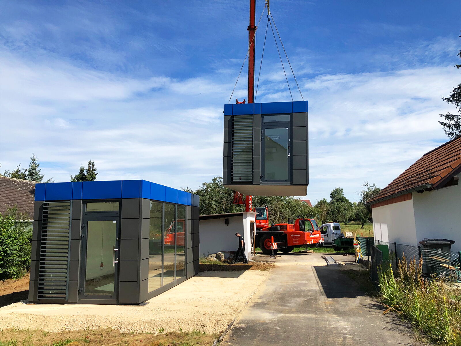 Montage eines Containers per Autokran neben bereits installiertem Container