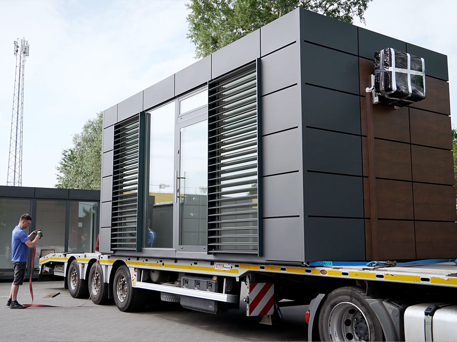 Transport eines modernen Bürocontainers mit Metallfassade auf einem Lkw