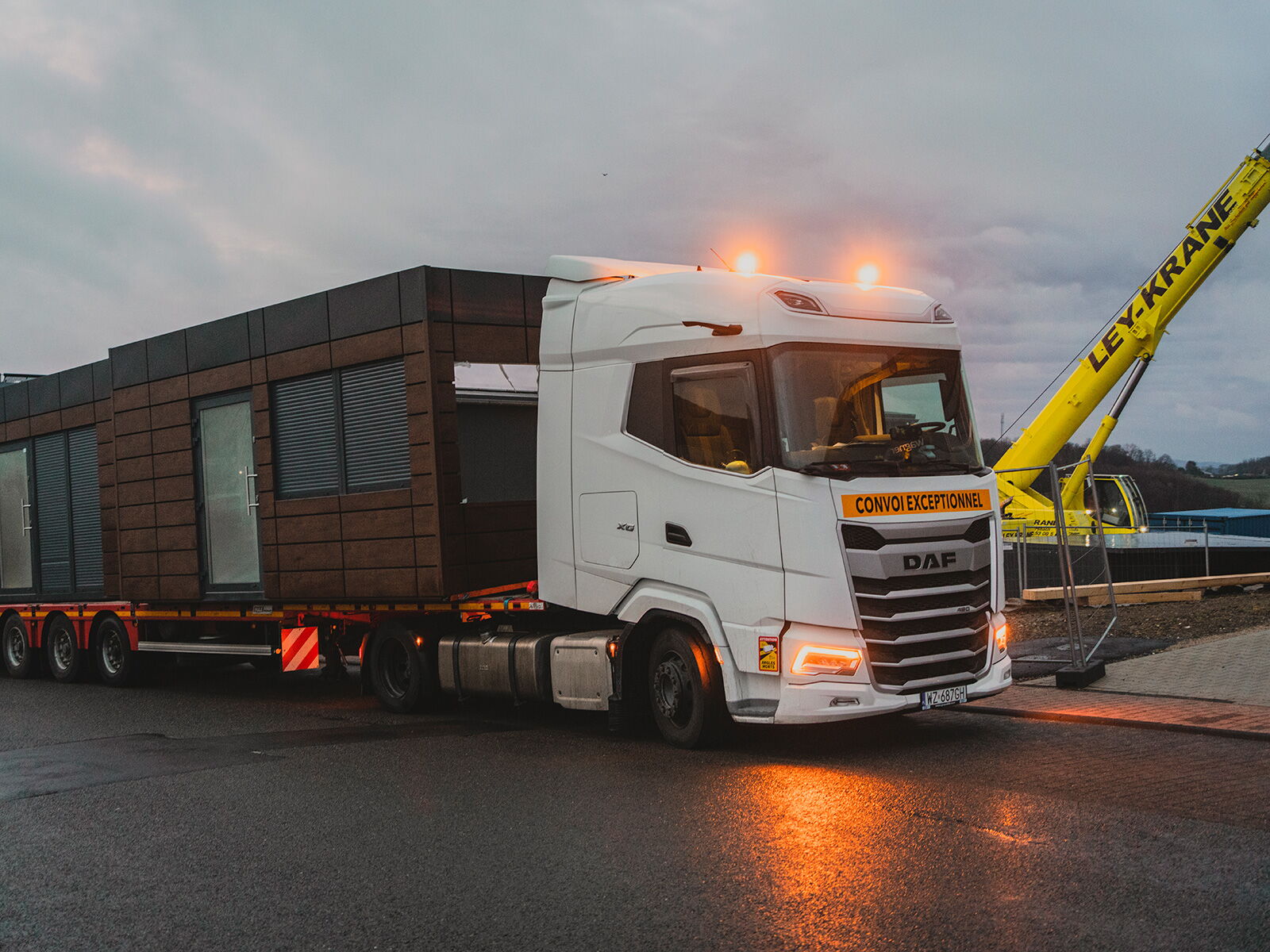LKW transportiert einen modernen Container auf einem Tieflader bei Dämmerung