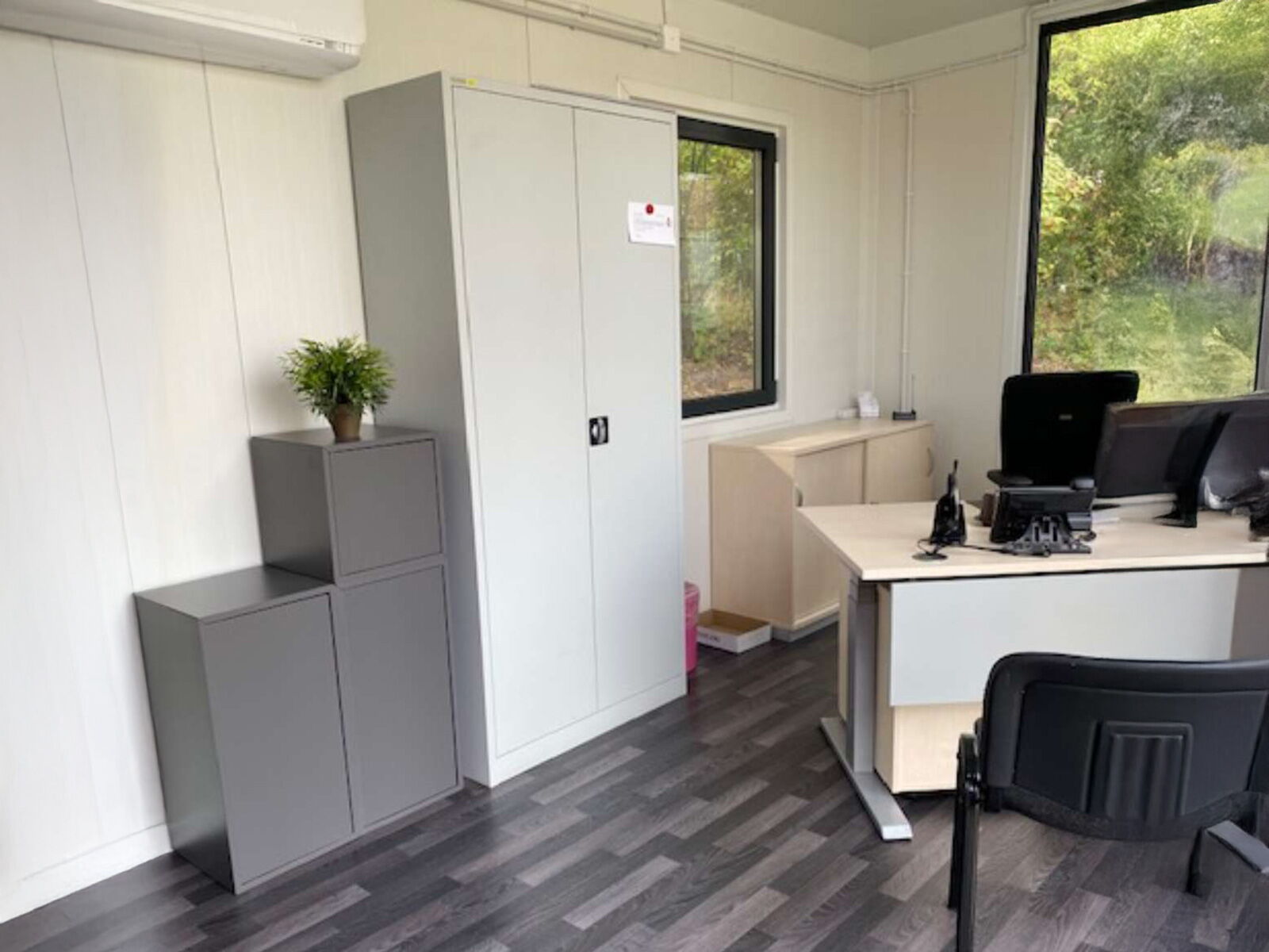 Büroinnenraum in einem Container mit Schreibtisch, Monitoren und Stauraum