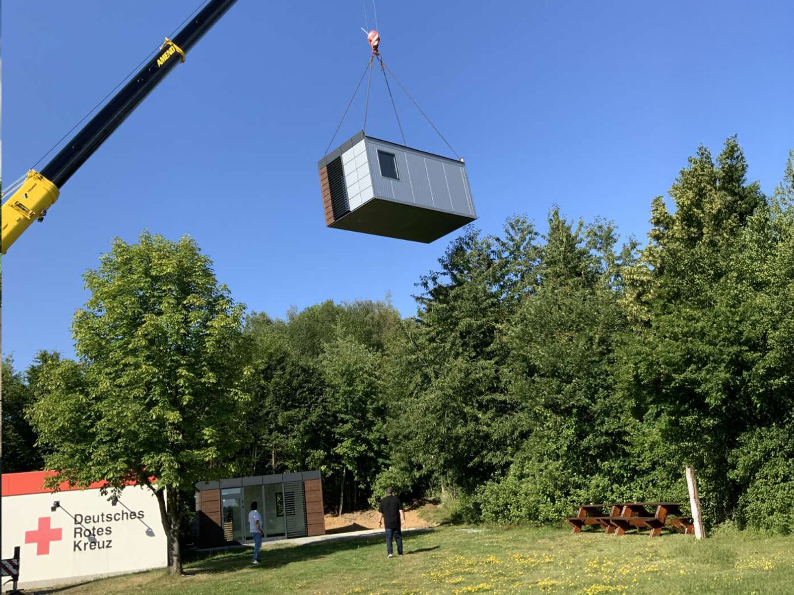 Container wird per Kran über ein Gelände nahe einer Rotkreuz-Station gehoben