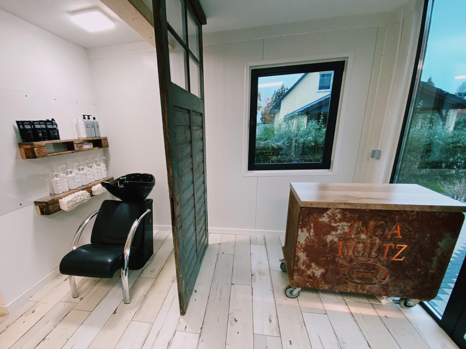 Innenraum eines Verkaufsmoduls mit Friseurstuhl, Waschbecken und rustikalem Empfangstresen