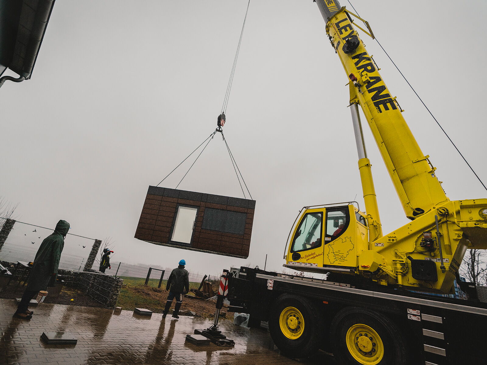 Modulcontainer wird per Kran auf der Baustelle versetzt