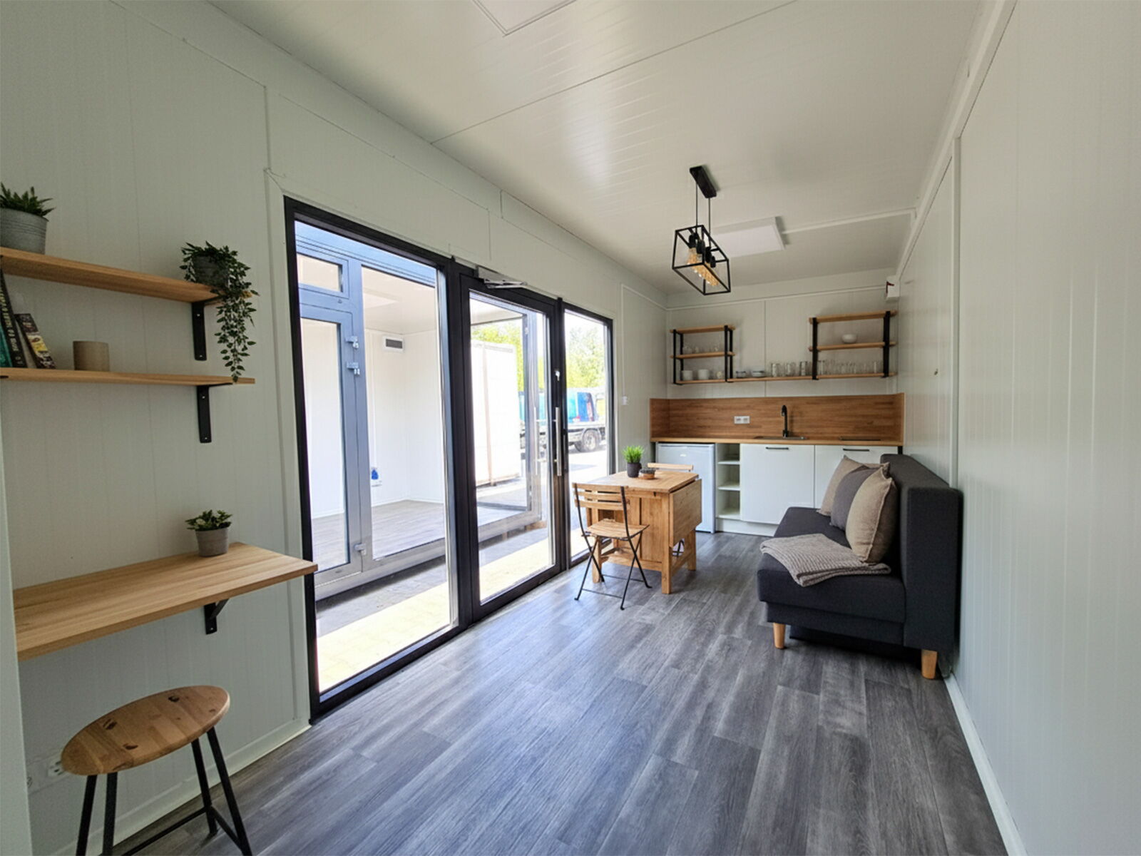 Moderner Innenraum eines Wohncontainers mit Küchenzeile, Esstisch und großer Glasfront