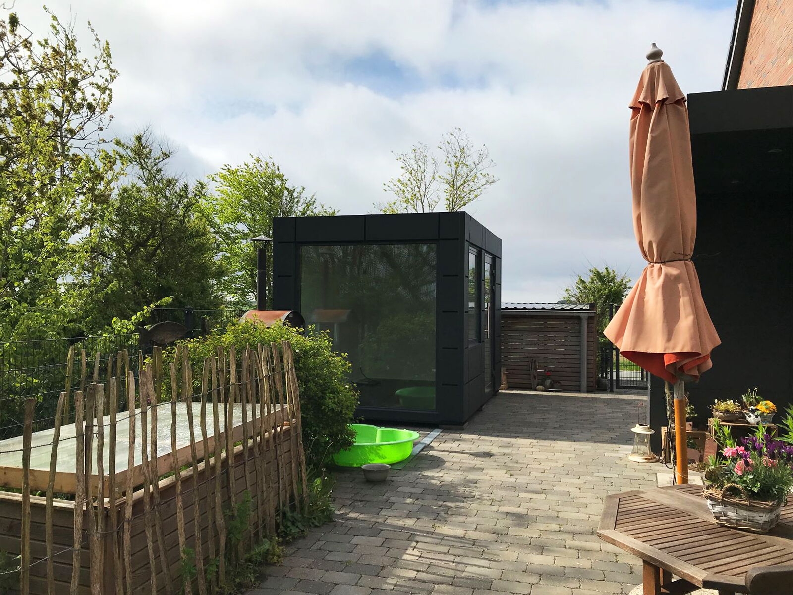 Moderner Bürocontainer mit dunkler Fassade im privaten Außenbereich