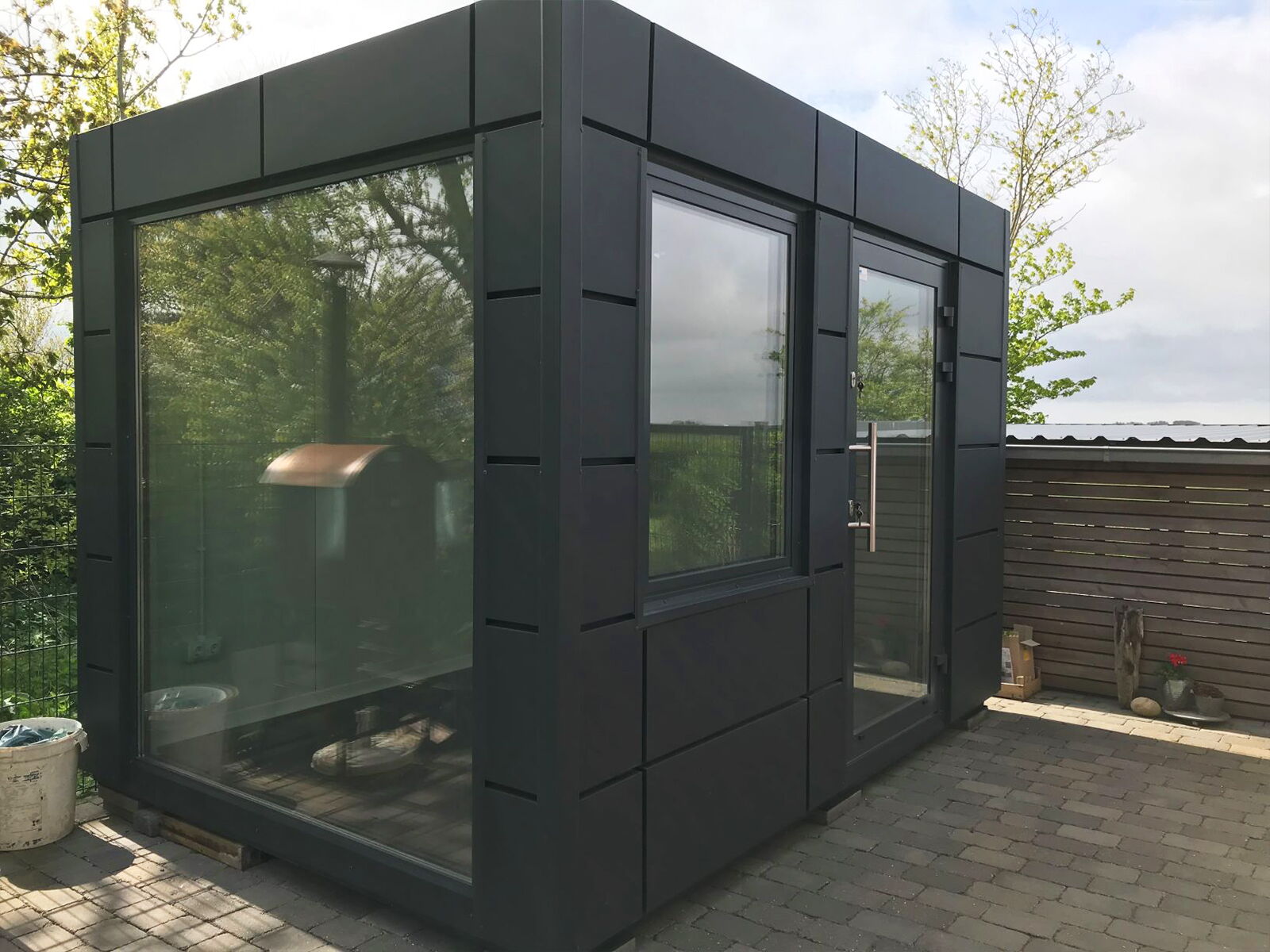 Kleiner Design-Modulcontainer mit großer Glasfront auf Terrasse