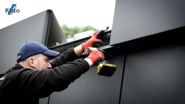 Handwerker montiert Verkleidung an Containerfassade