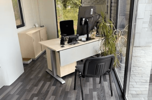 Innenansicht eines modernen Bürocontainers mit Arbeitsplatz und Fensterfront