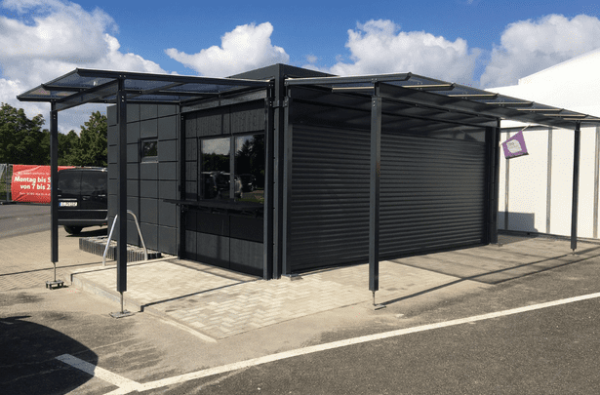Bäckerei-Container mit moderner schwarzer Fassade und Vordach