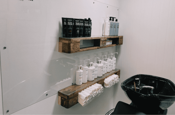 Waschplatz mit Wandregalen aus Paletten und Pflegeprodukten im Friseurcontainer von Inga Holtz