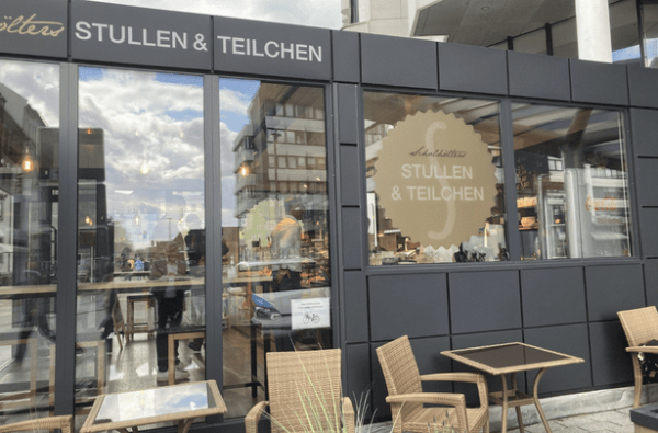 Verkaufscontainer der Bäckerei Scholhölter mit Glasfassade, Logo und Sitzplätzen außen