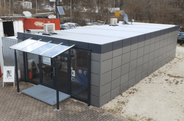 Schrägansicht des Containers vom T-Z-N Technik Zentrum mit Flachdach und Glasvordach am Eingang