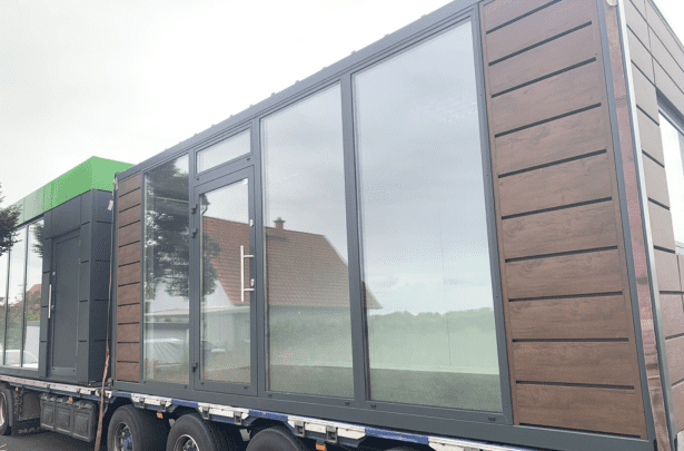 Moderner Bürocontainer auf einem Tieflader beim Transport zur Aufstellung