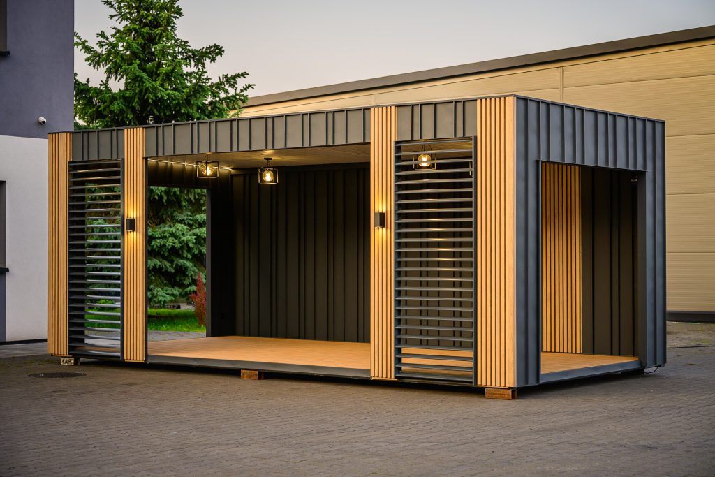 Moderne Pergola in Container-Optik mit Holzlamellen und schwarzem Stahlrahmen als stilvolle Outdoor-Lounge